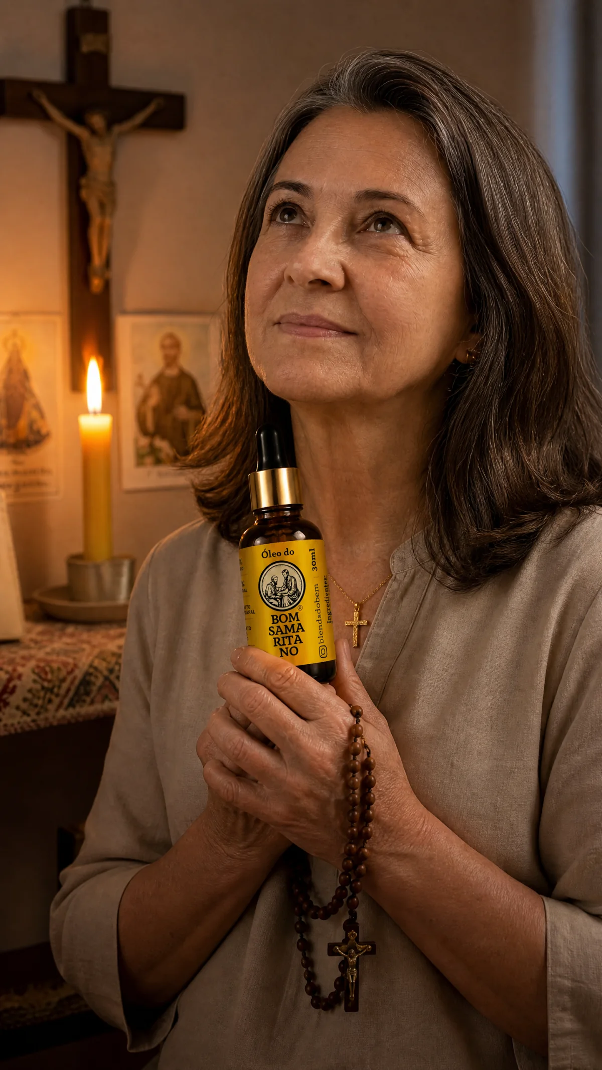 Mulher em oração segurando o Óleo do Bom Samaritano e um terço diante de uma vela e um crucifixo